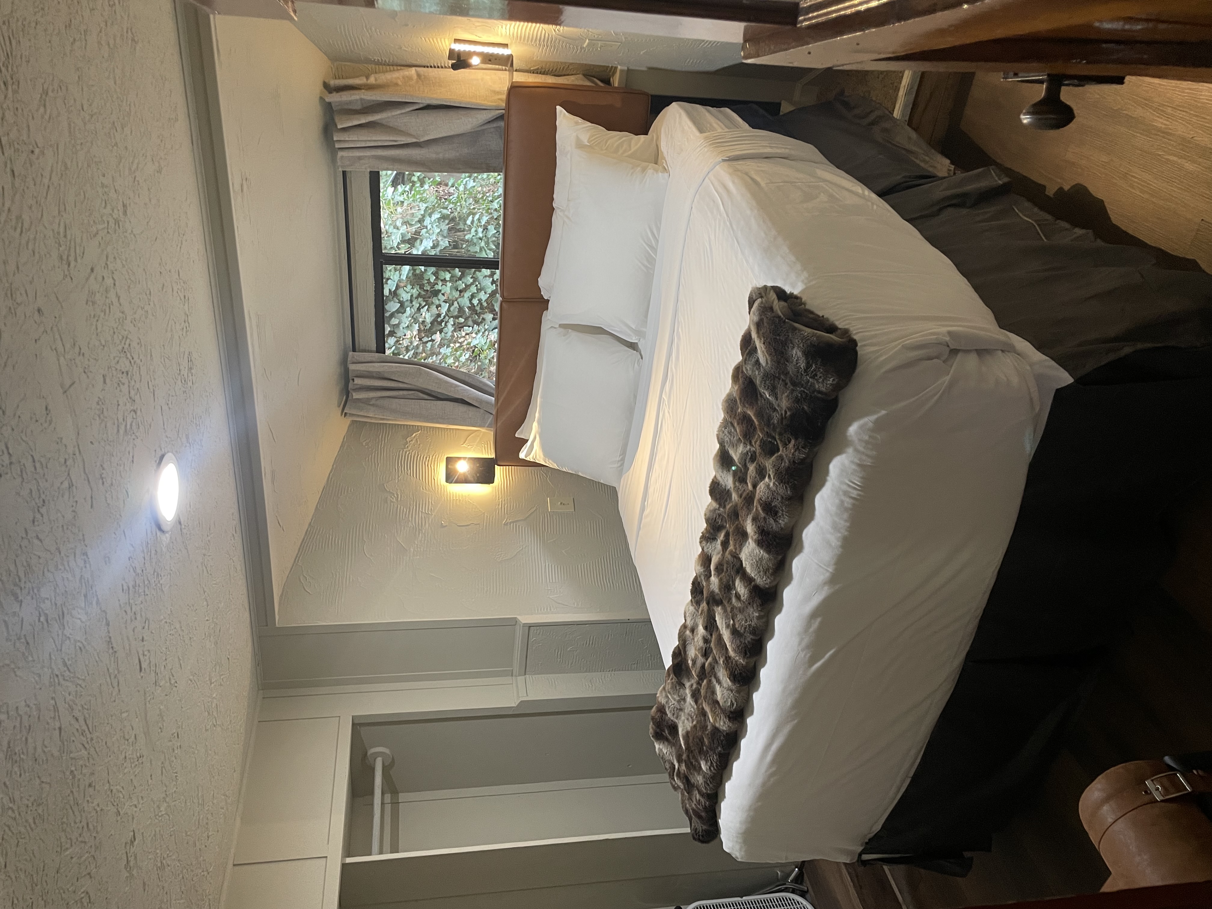 A wide view of a hotel room with a large bed, window, closet, and lamps.
