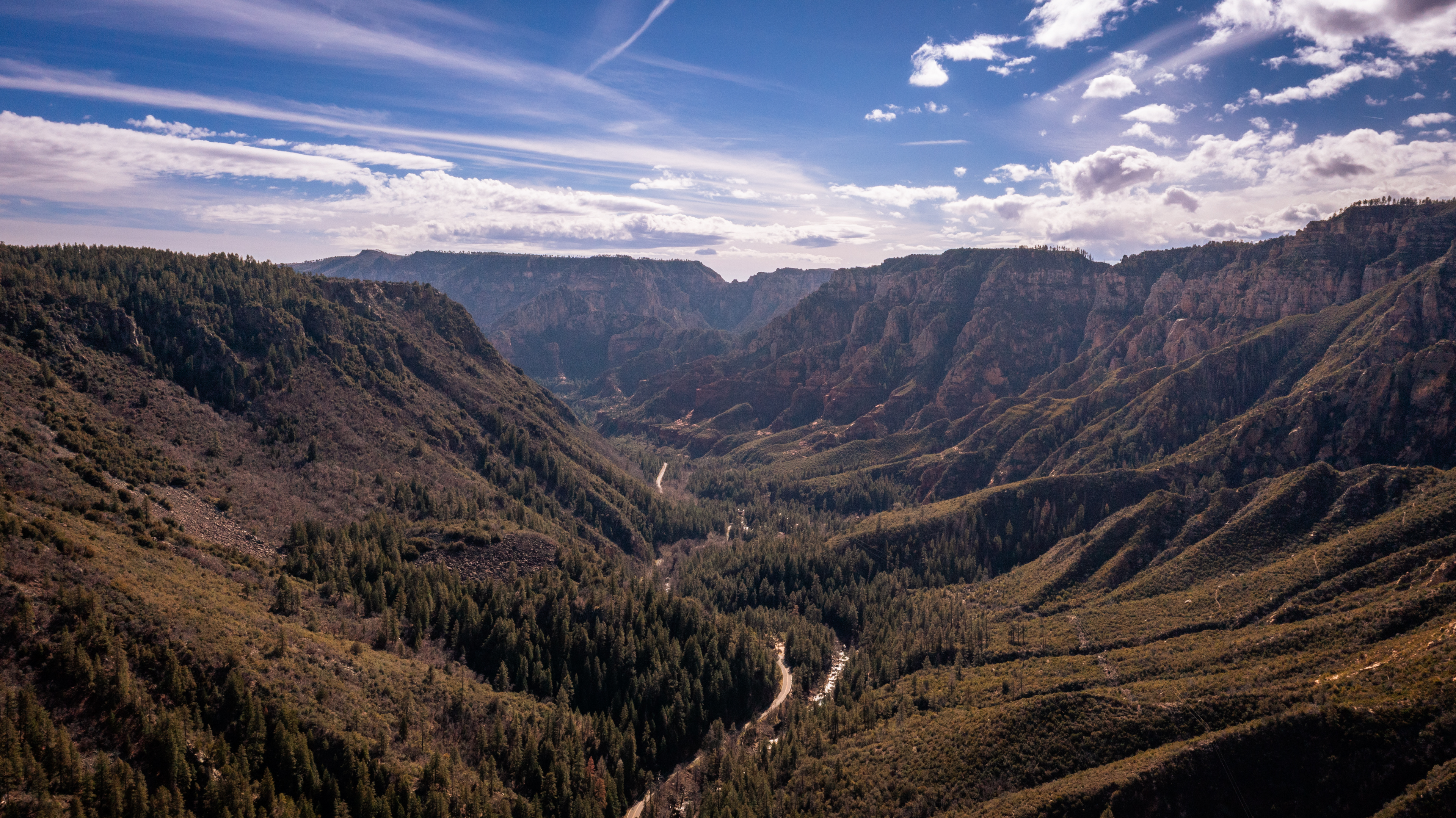 A scenic view of a mountain valley with a blue sky and clouds.