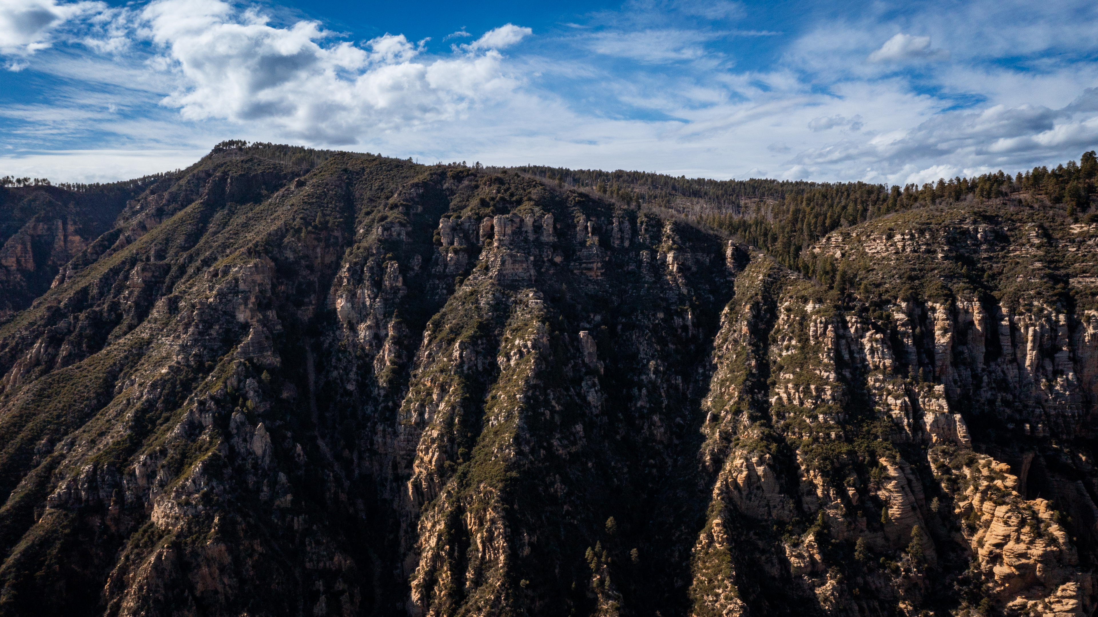A wide view of a mountain range with a blue sky and clouds.